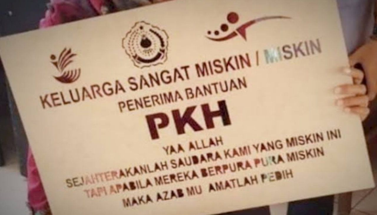 ILUSTRASI. Seorang warga memegang papan bertuliskan penerima bantuan PKH. (doc. Istimewa/KLIKJATIM.Com)